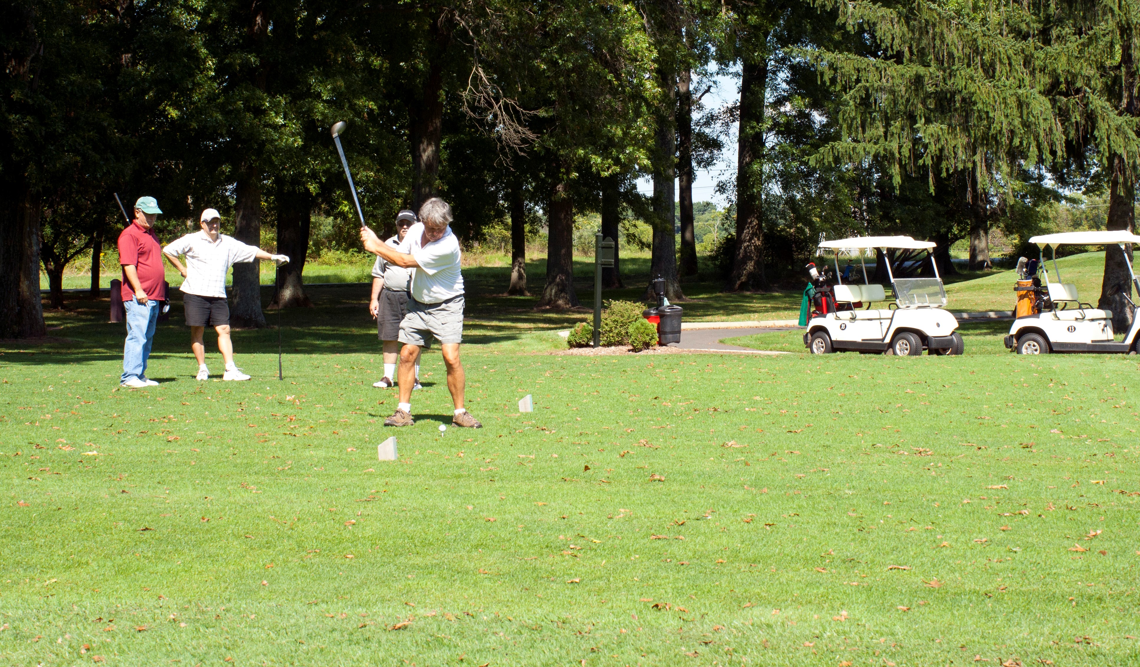 A group of men golfing near golf carts on the green