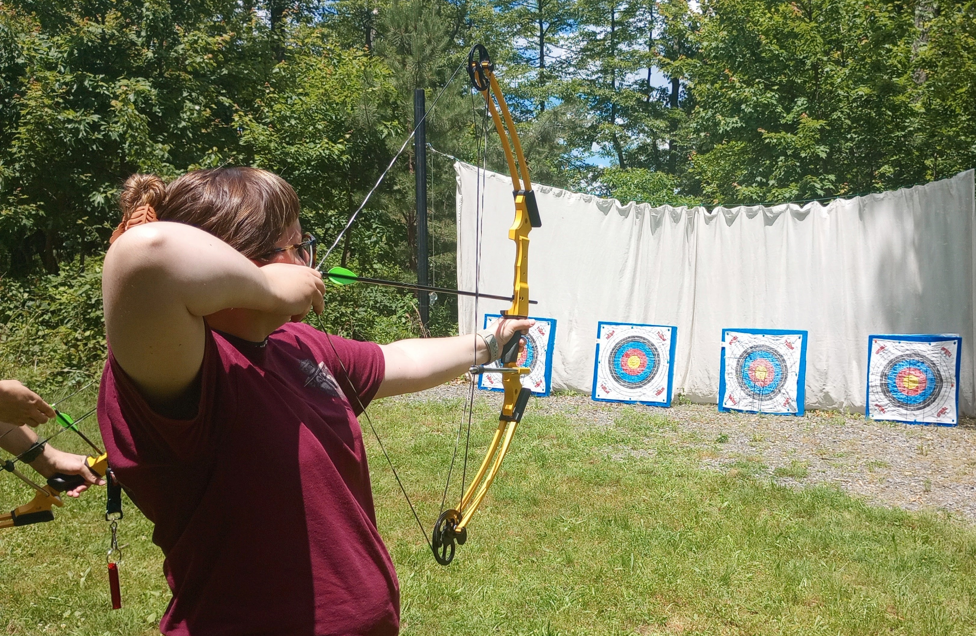 A woman practicing target shooting with a bow and arrow