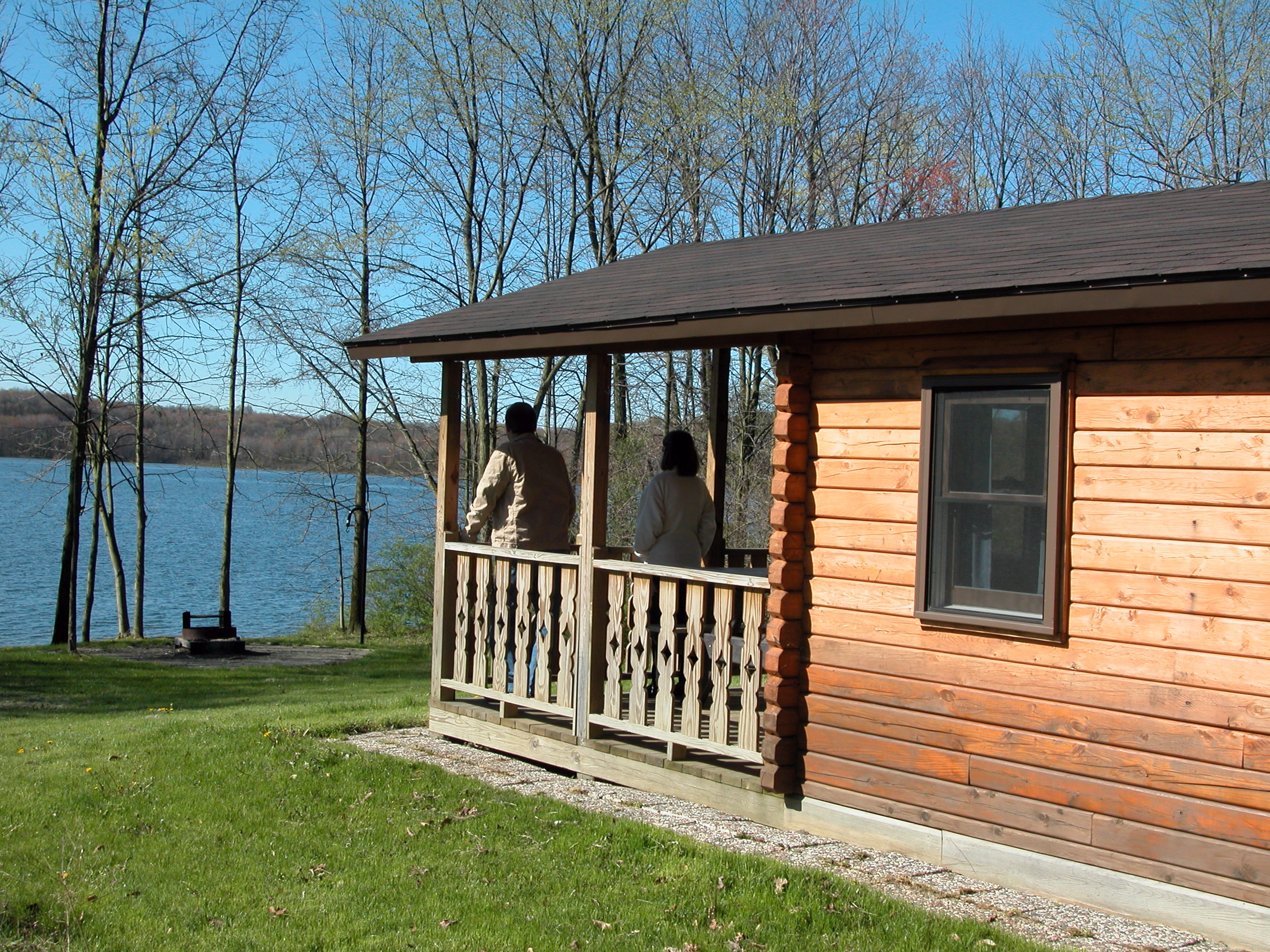 Two people on a cabin porch overlooking a lake