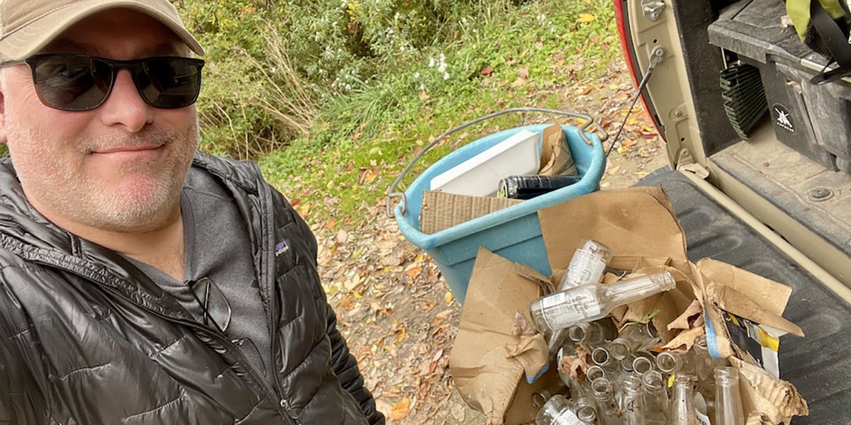 Man taking a selfie showing all of the trash he collected while participating in the Adopt an Access Program. Photo courtesy of Backcountry Hunters and Anglers.