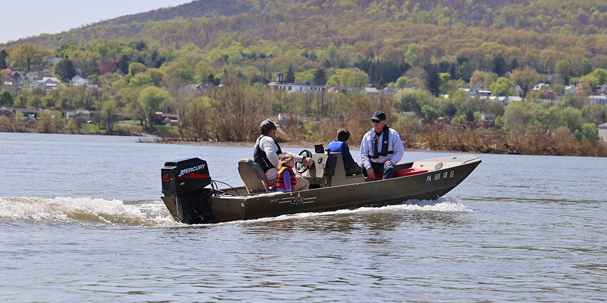 Family of four, all wearing life jackets, ride in a powerboat along the Susquehanna River