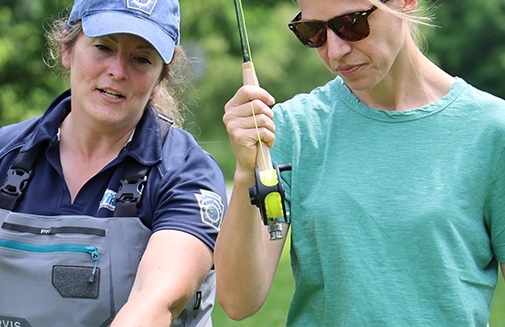 PFBC Educator teaches a woman how to cast a fly fishing rod