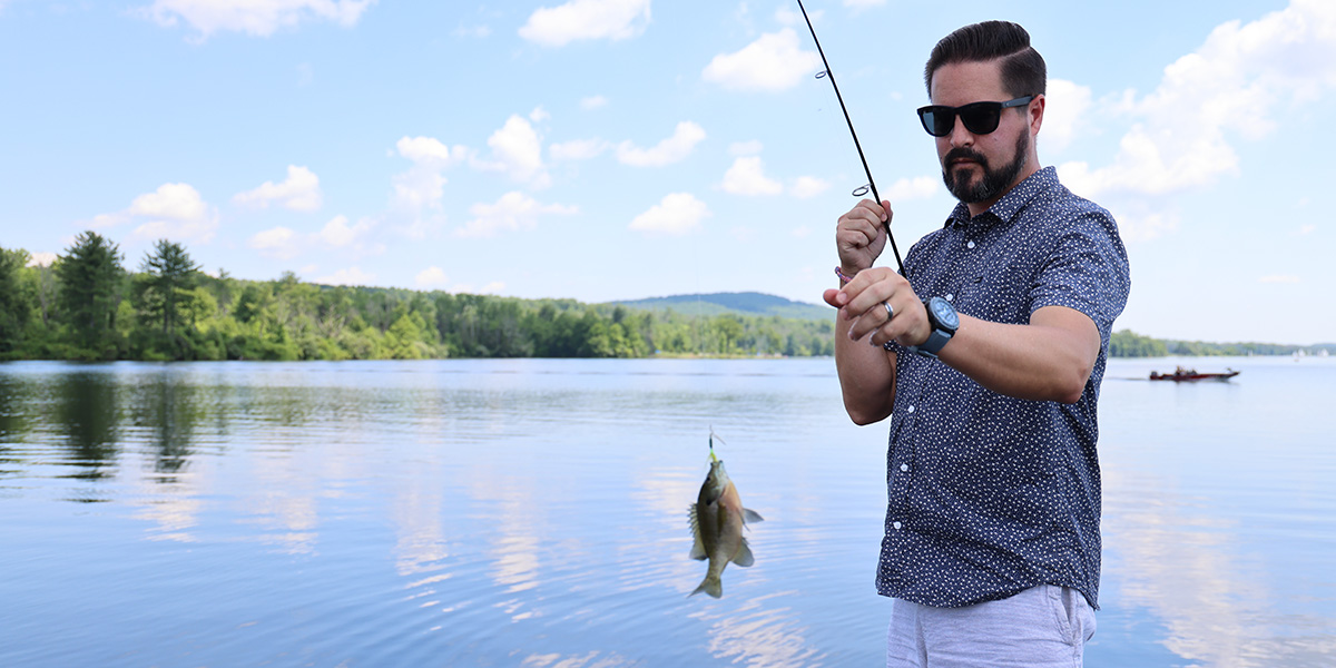 Man on lake with fishing rod and fish on fishing line 