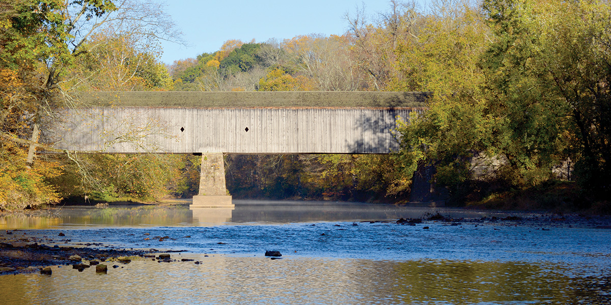 Wide shot of wooden covered walking bridge over Neshaminy Creek in Tyler State Park in Southeast PA