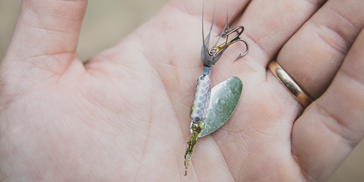 Close-up of a person holding an artificial spinner lure.