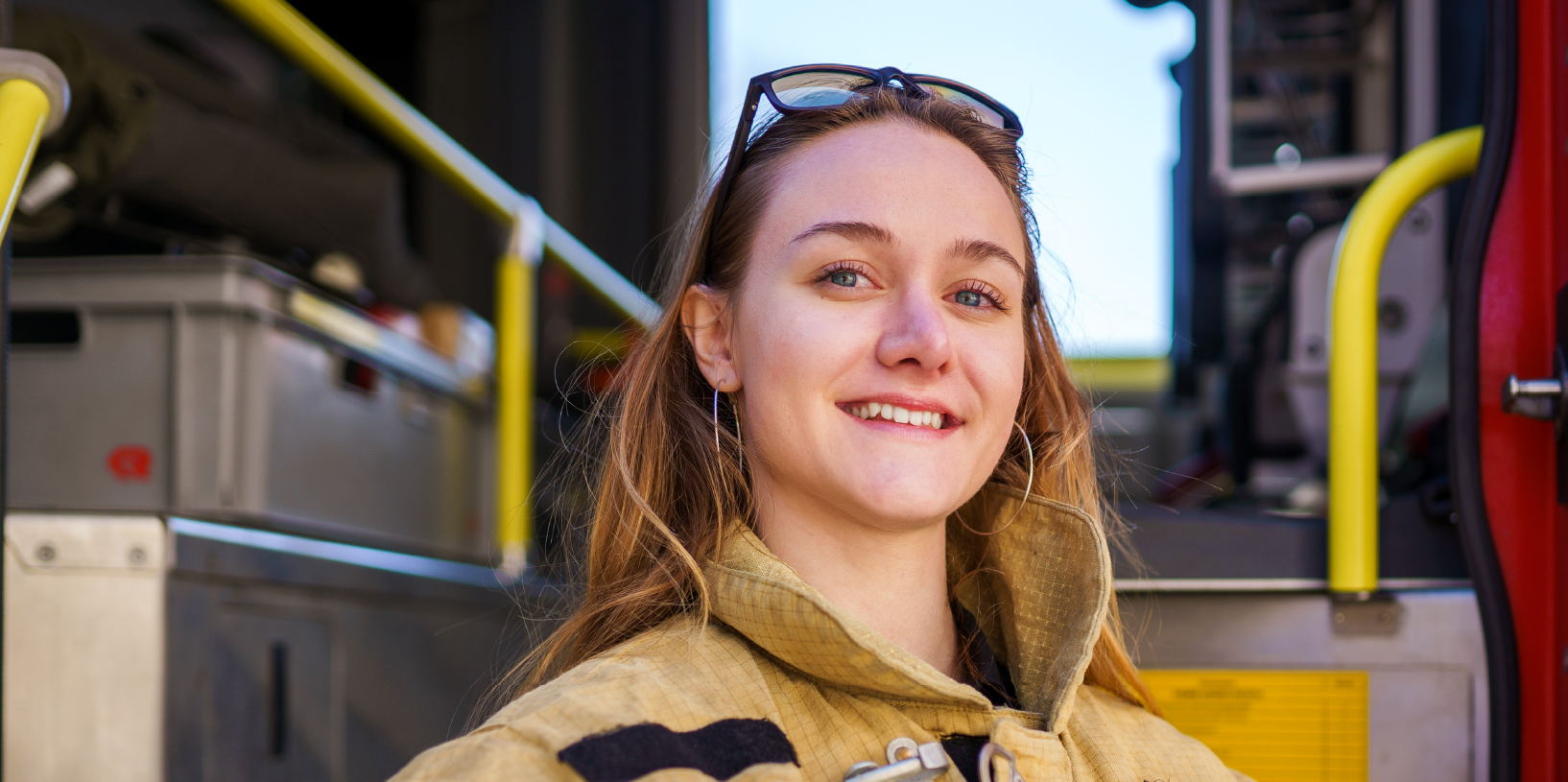 A young girl poses in firefighter gear.