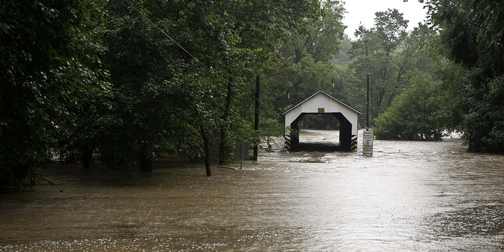 Floods overtake a covered bridge.