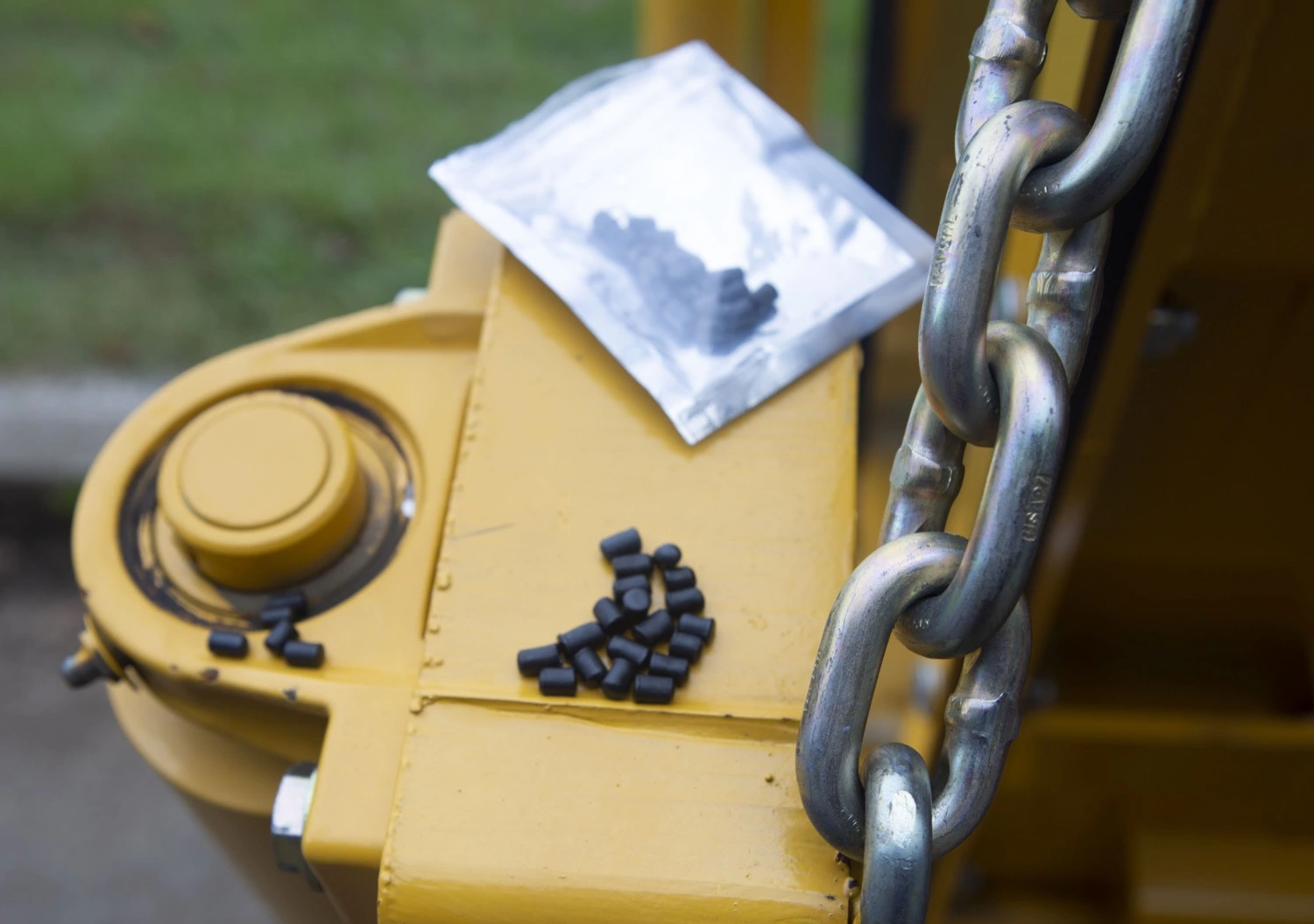 An image of small, black recycled plastic asphalt modifier pellets sitting inside and outside a package on the back of a paving truck.