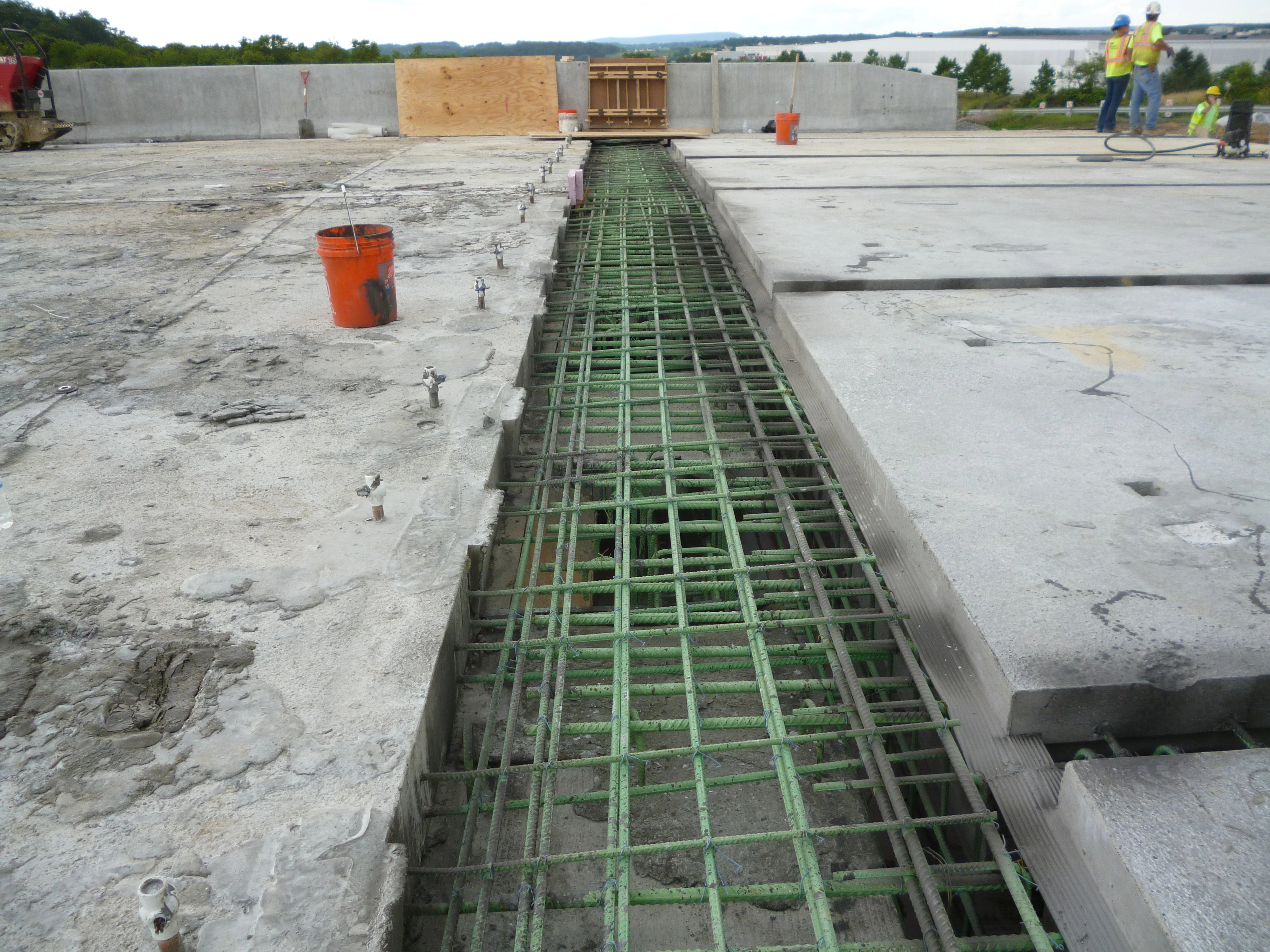 An image of construction workers using Ultra-High Performance Concrete between prefabricated bridge elements.