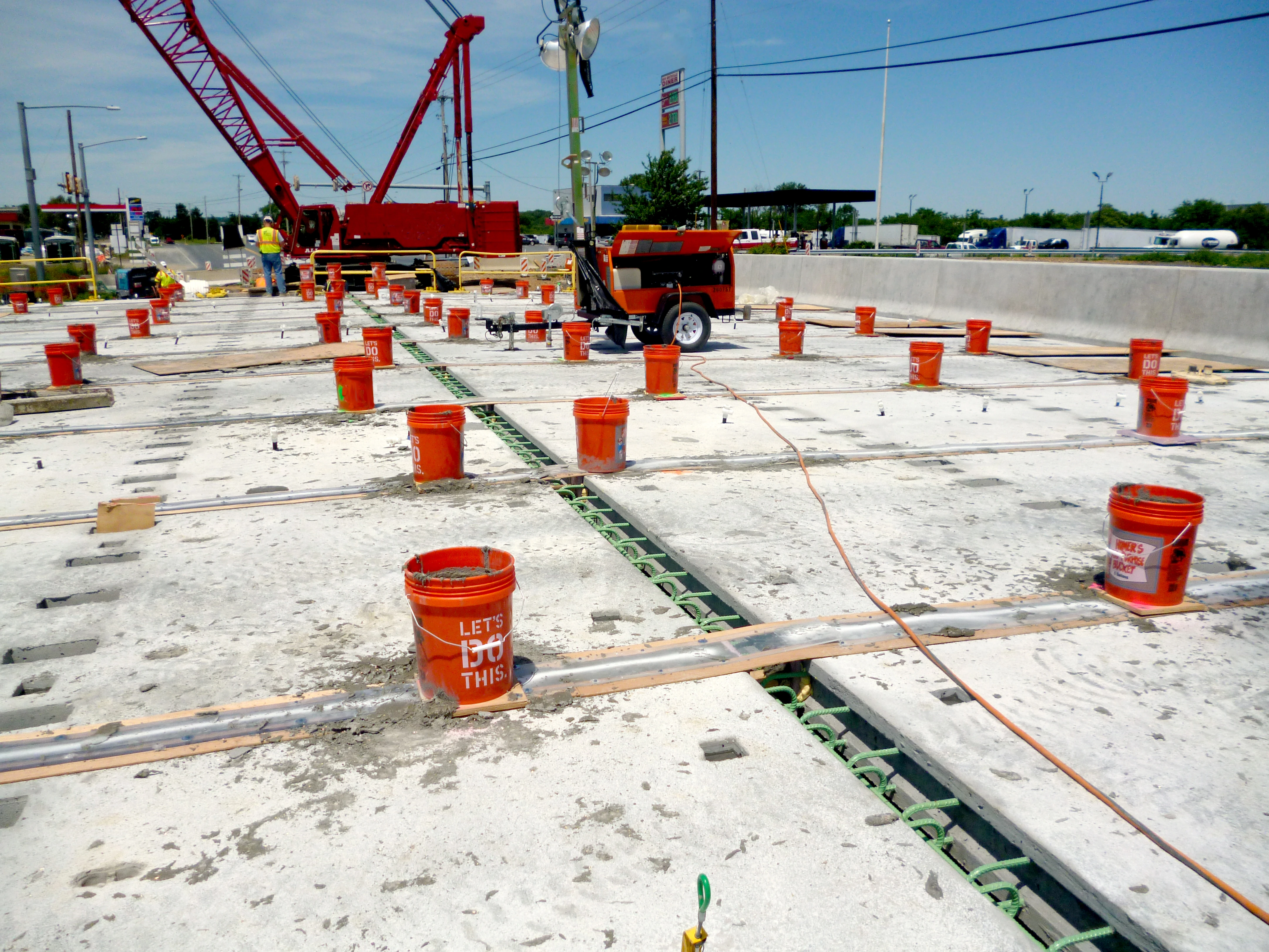 An image of construction workers using Ultra-High Performance Concrete between prefabricated bridge elements.