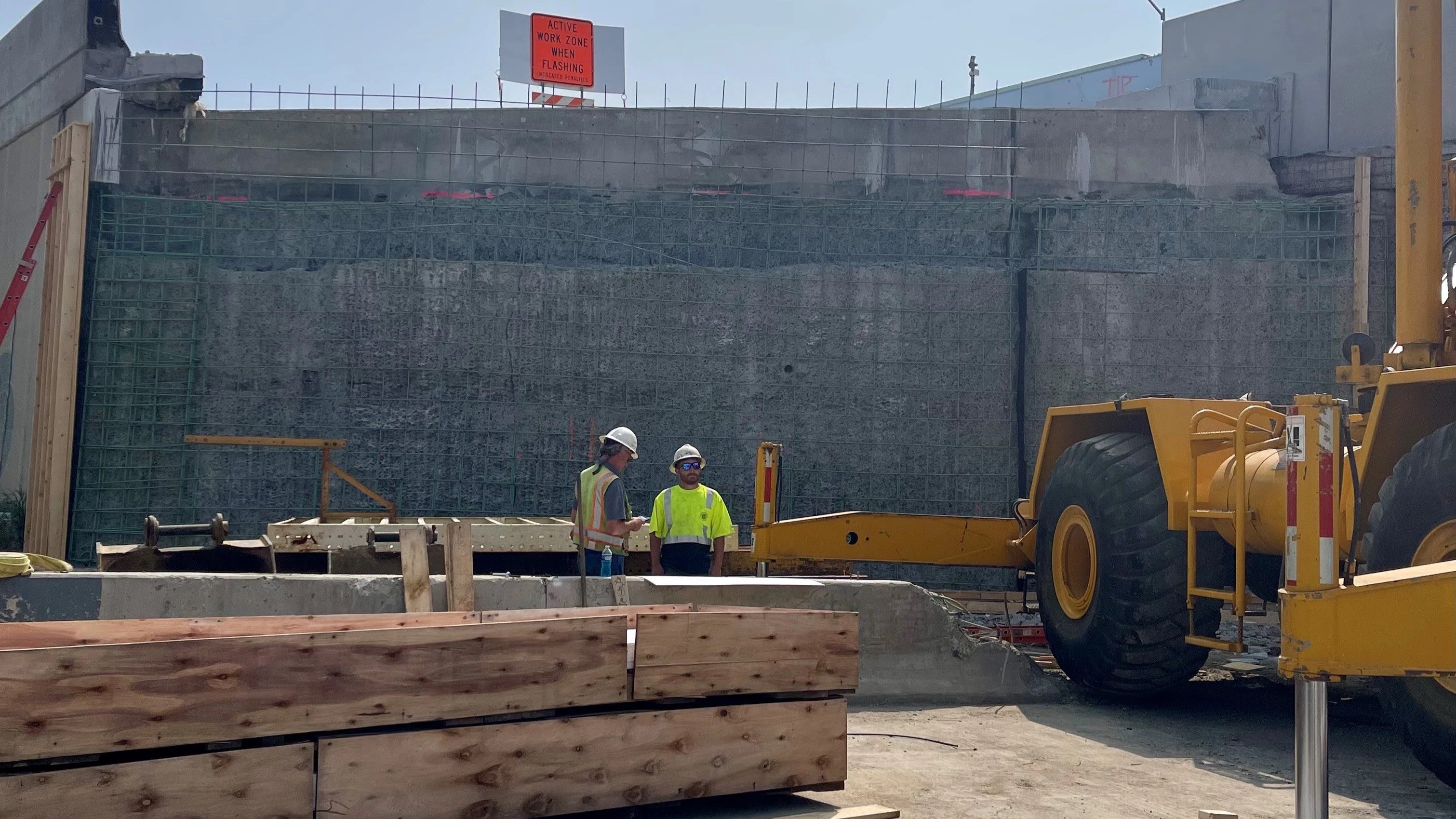 Two construction works in white hard hats and yellow safety vest stand at the worksite where the reconstruction of the permanent Cottman Avenue interchange has begun