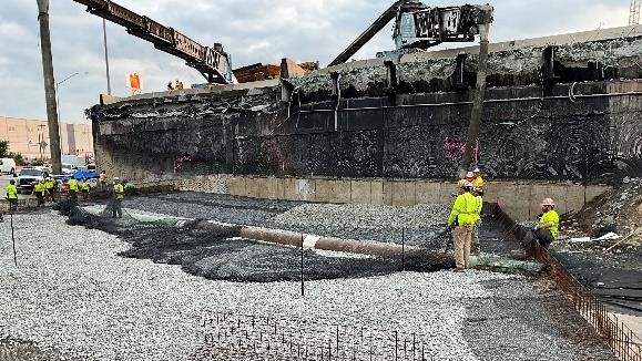 Construction works in hard hats and yellow safety vests stand 