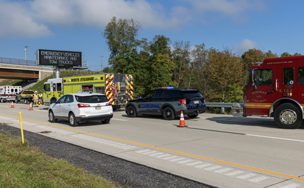 An image of two fire trucks, a police car and an ambulance at the scene of an incident with an incident message displayed on a large message board in the background