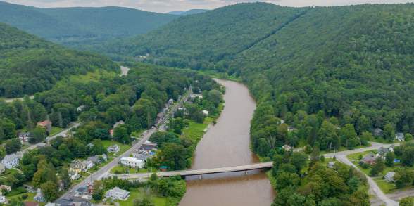 Flood water overtakes a neighborhood of homes and trees.