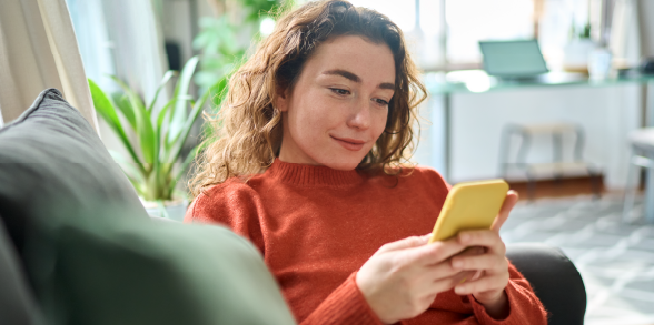 A woman looks at her phone while relaxing on a comfy couch.