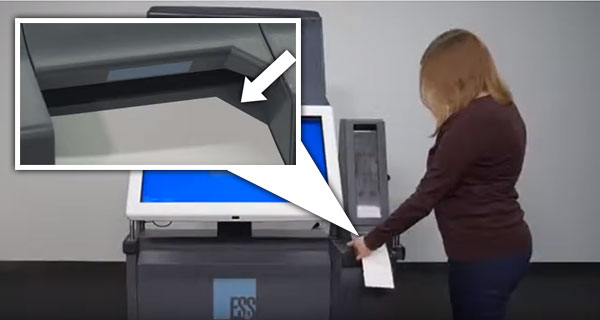 A person placing their ballot into the marking device