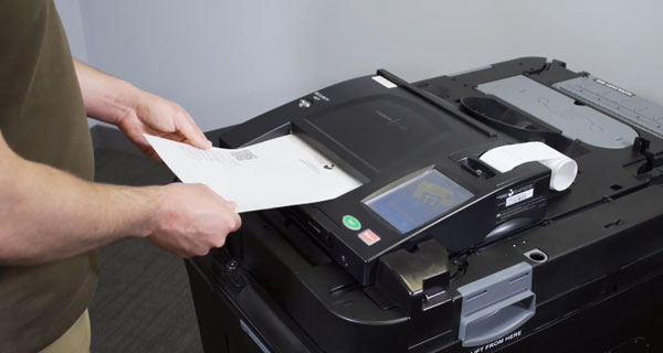 Person putting their ballot into the ballot scanner